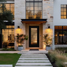 Black full lite fiberglass entry door with Rill glass on a stone and white home at dusk